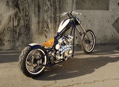 a white and blue motorcycle parked in front of a concrete wall with graffiti on it