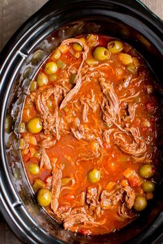 a slow cooker filled with meat and olives