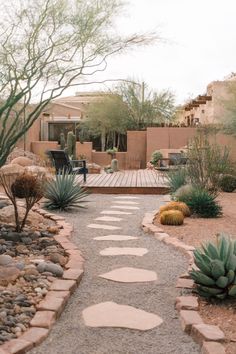 a pathway made out of stones leads to a patio with cactus and succulents