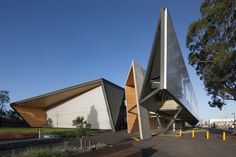 two triangular shaped buildings sit next to each other on the side of a road in front of trees