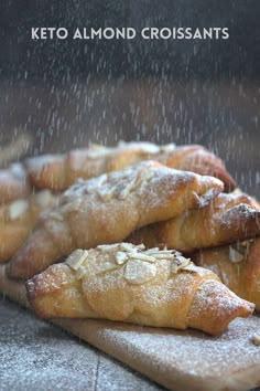 some breads sitting on top of a wooden cutting board under a rain soaked window