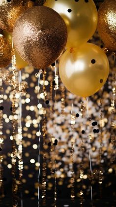 gold and black balloons are hanging from the ceiling with confetti streamers around them