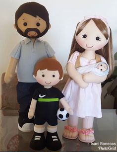 three dolls are standing next to each other in front of a white wall, one is holding a baby and the other has a soccer ball