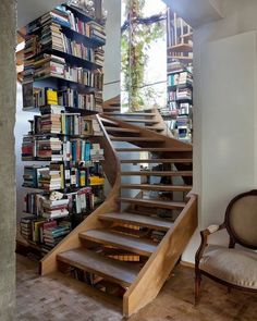 there is a book shelf with many books on it and a chair next to it