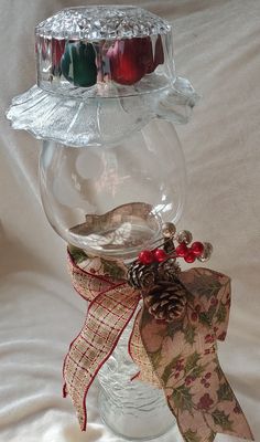 a clear glass bowl with pine cones and red berries in it on a white background