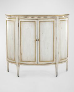 an antique white cabinet with gold trimmings on the doors and drawers is shown