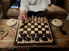 a person playing chess on a table with wine glasses and other items around it in front of them