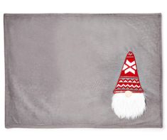 a gray towel with a red and white gnome's hat on it, sitting in front of a grey background