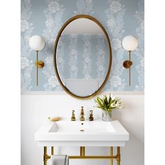 a white sink sitting under a mirror next to a gold faucet and wall mounted light