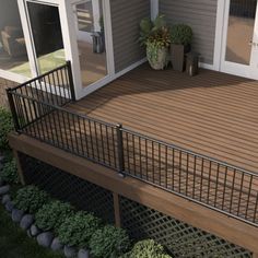 a deck with railings and potted plants on the other side, in front of a house