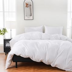 a bed with white sheets and pillows in a room