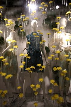 there are many mannequins with yellow flowers in front of them on display