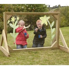 two children are looking in a mirror with flowers on it and one child is holding a toothbrush