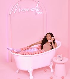 a woman sitting in a bathtub with pink balls