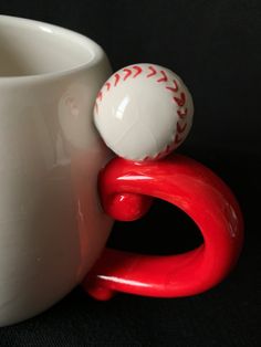 a red and white baseball sitting on top of a cup