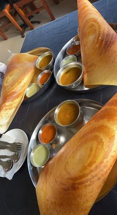 some food is sitting on a table with bowls and spoons next to each other