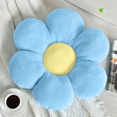 a blue flower pillow sitting on top of a bed next to a cup of coffee