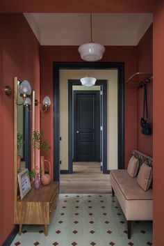 the hallway is painted red and has two couches on either side of the door