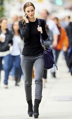 a woman is walking down the street talking on her cell phone and holding a purse