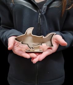 a person holding an object in their hands with the shape of a shark on it