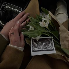 a woman is holding flowers in her lap while she sits on the car's steering wheel