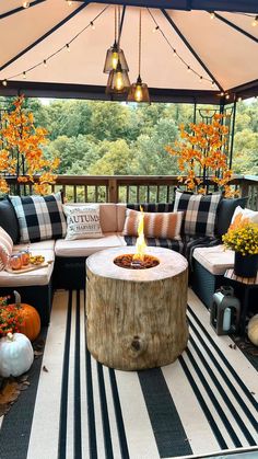 an outdoor living area with black and white striped rugs, plaid pillows, pumpkins and candles