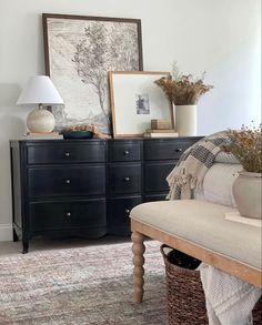 a living room with a couch, dresser and pictures hanging on the wall above it