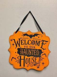 a sign that says welcome to our haunted house hanging on the wall in front of a door