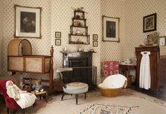 an old fashioned living room with antique furniture and pictures on the wall, including a baby's crib