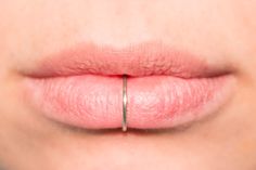 a woman's lips with a gold ring on her lip and the tip of her nose