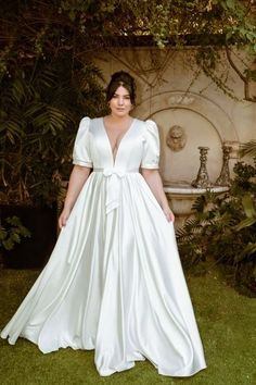 a woman wearing a white dress standing in the grass