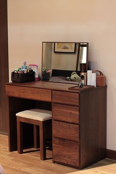 a wooden desk with a mirror, stool and other items on top of the table