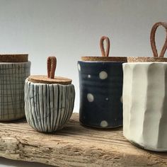 four ceramic pots sitting on top of a wooden shelf