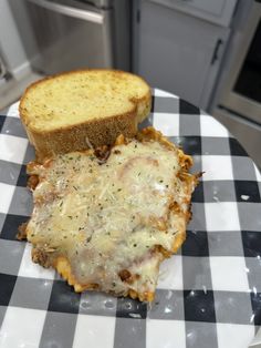 a piece of bread with cheese and meat on it sitting on a checkered plate