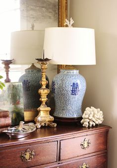 a blue and white vase sitting on top of a wooden dresser next to a lamp