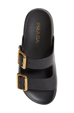 Golden buckles and Prada's iconic logo detail this lugged-sole sandal topped with a duo of buckled straps that offer a custom, secure fit. 1 1/4" (32mm) heel; 1" platform (size 38.5) Adjustable straps with buckle closure Contoured footbed Leather upper and lining/synthetic sole Made in Italy Designer Shoes Luxury Calf Leather Slides With Buckle Closure, Luxury Black Sandals With Rectangular Buckle, Designer Leather Sandals With Gold Buckle, Luxury Leather Sandals With Gold Buckle, Luxury Leather Slides With Tang Buckle, Luxury Slides With Buckle Closure, Luxury Black Slides With Buckle Closure, Designer Black Sandals With Rectangular Buckle, Luxury Double Strap Sandals With Tang Buckle