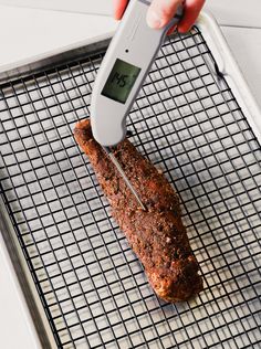 a person is using an electronic thermometer to measure meat on a grill pan