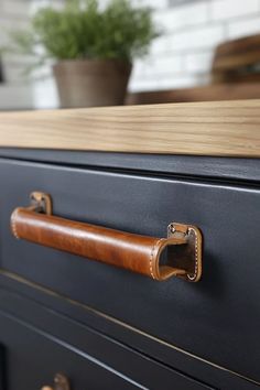 a close up of a drawer with handles on it and a potted plant in the background