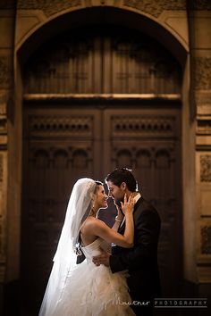 a bride and groom standing in front of an ornate wooden door at their wedding reception