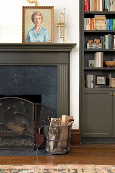 a living room with a fire place and bookshelf in the corner, along with a painting on the wall