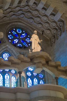 a statue in front of a large stained glass window