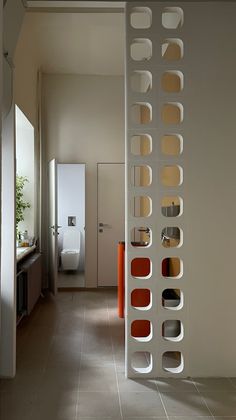 a room divider in the middle of a tiled floored hallway with orange and white accents