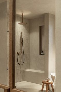 Moderne douchehoek met warme, natuurlijke tinten. De douche heeft een ingebouwde zitbank in betonlook en is afgewerkt met beige wandtegels. Bronskleurige douchekop en handdouche voegen een vleugje luxe toe. Niche met verzorgingsproducten ingebouwd in de muur voor functionaliteit en stijl. Een kleine houten krukje buiten de douche zorgt voor een uitnodigende sfeer en biedt ruimte voor accessoires. Zen Bathrooms, Interior Architects, Barn Style House Plans, Willemstad, Bathroom Redesign, Bathroom Photos, Master Bath Remodel, Budget Bathroom