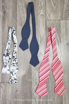 three ties laid out on a wood floor with one red, white and blue tie