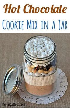 a jar filled with cookies and marshmallows sitting on top of a doily