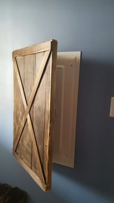 a wooden door hanging from the side of a blue wall next to a white box