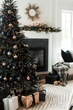 a decorated christmas tree in a living room with black and gold ornaments on the top