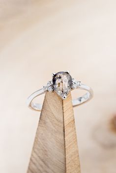 a diamond ring sitting on top of a wooden stand