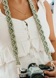 a woman holding a camera in her hand and wearing a crocheted white dress