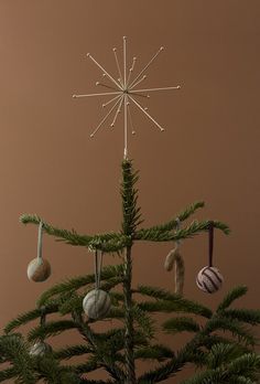 a small christmas tree with ornaments hanging from it's branches in front of a brown background